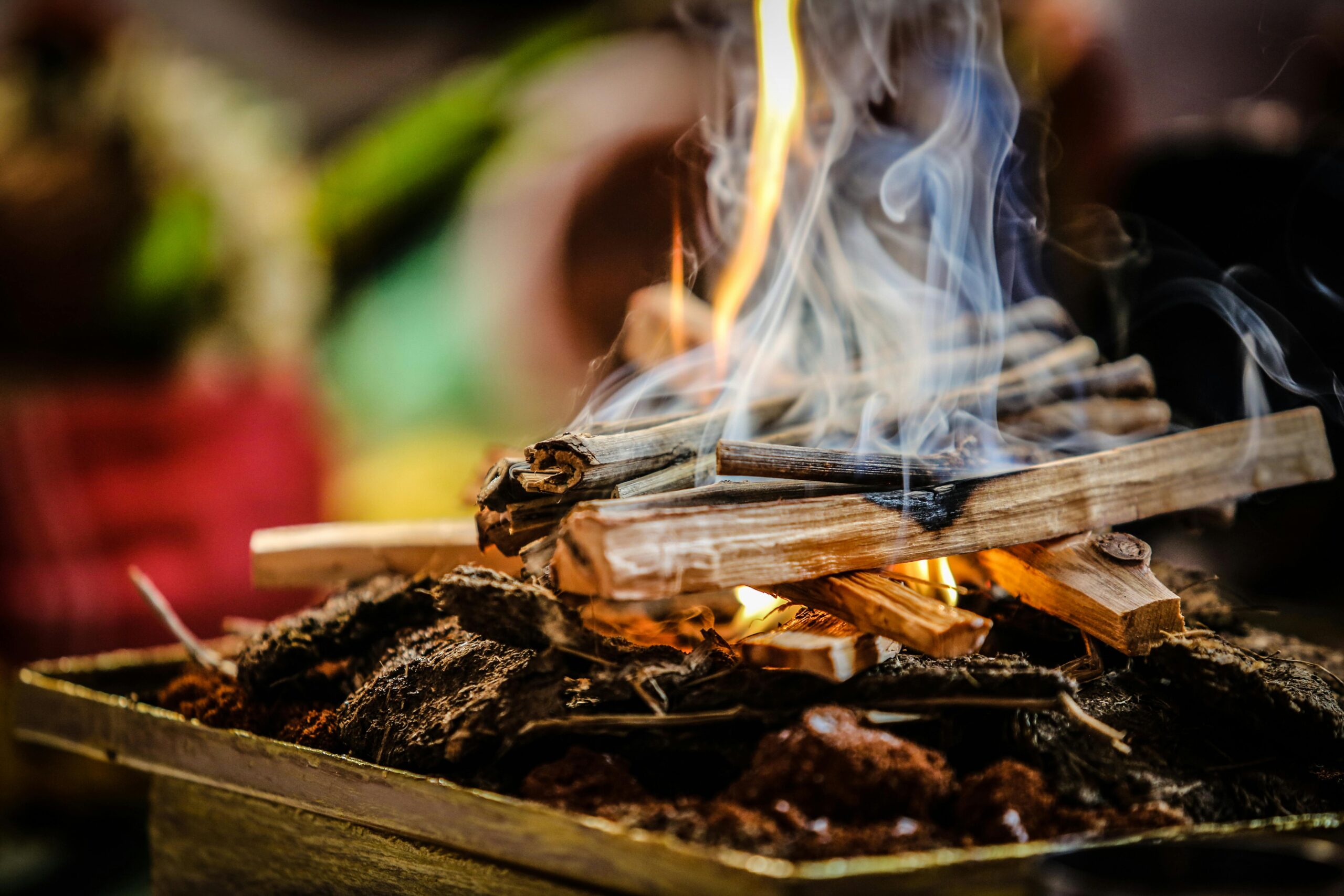 A detailed close-up of firewood burning with smoke rising, creating a warm and vibrant visual.